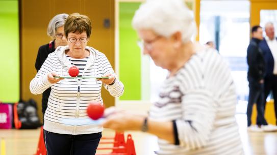 Twee ouderen houden een bal in balans, klik voor een vergroting