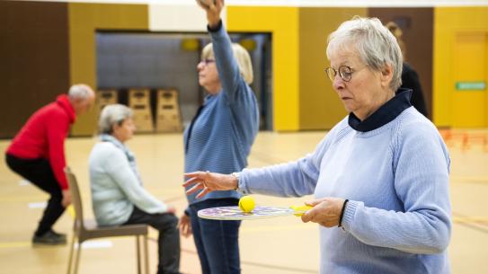 Vier ouderen die oefeningen doen in een gymzaal, klik voor een vergroting