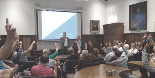 Zaal met mensen waar een presentatie wordt gehouden