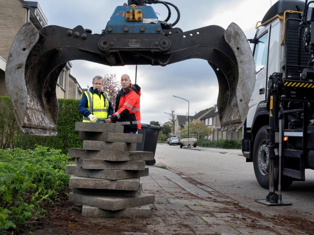 Een vrachtwagen haalt tegels op bij een tuin