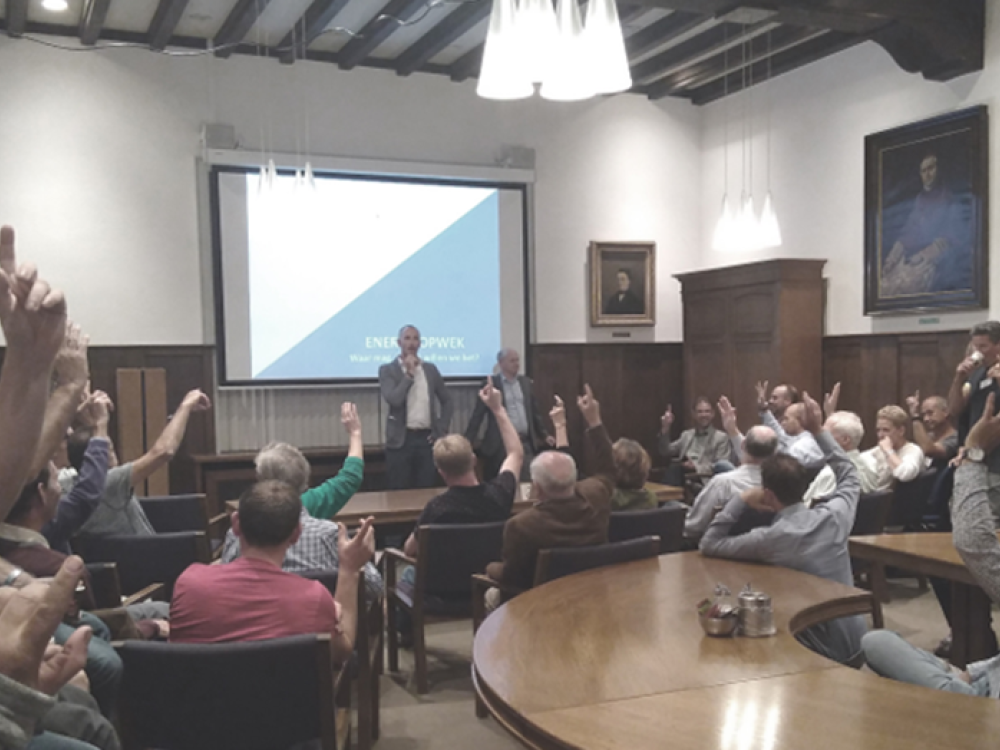 Zaal met mensen waar een presentatie wordt gehouden