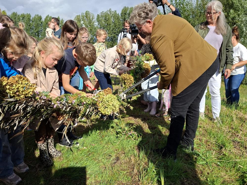 Wethouder van Laarhoven knipt samen met kinderen een versierde wilgentak door
